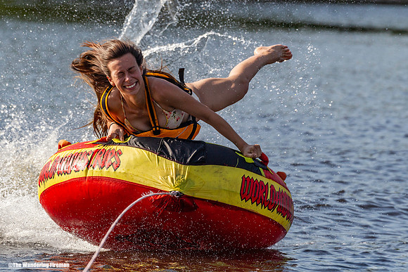Young girl hangs on to her tube behind a boat