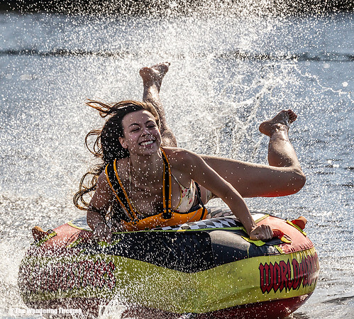 Pretty young girl rides a tube behind a boat