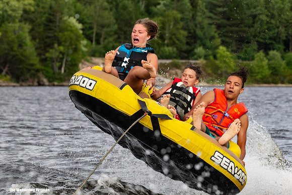 Three scared teenagers on a tube being pulled behind a boat
