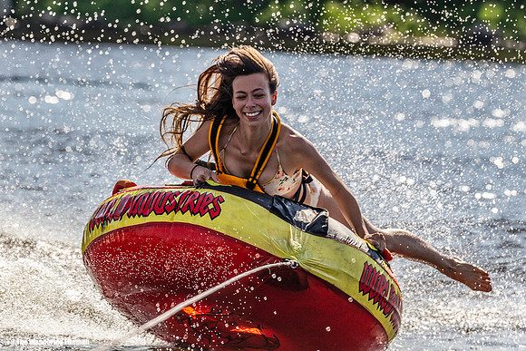Pretty girl has fun riding a tube behind a boat
