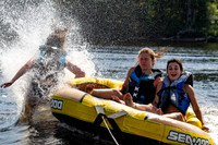 A teen falls out of a tube being pulled behind a boat