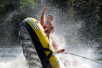Three boys joy riding in a tube being pulled by a boat