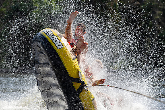 Three boys joy riding in a tube being pulled by a boat