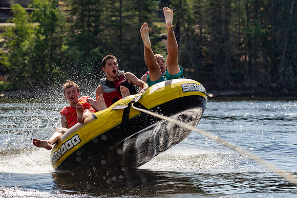 Three teens have tubing fun behind a boat