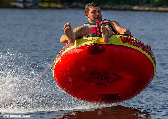 Screaming along riding a tube behind a boat