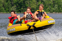 Three boys having fun on a tube being pulled behind a boat