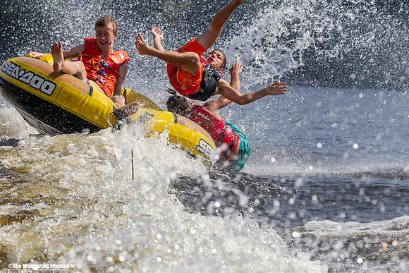 Three young teens are ejected from a tube behind a boat