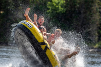 Three boys flip a tube being pulled behind a boat