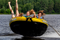 Three teen girls catching air on a tube being pulled behind a boat