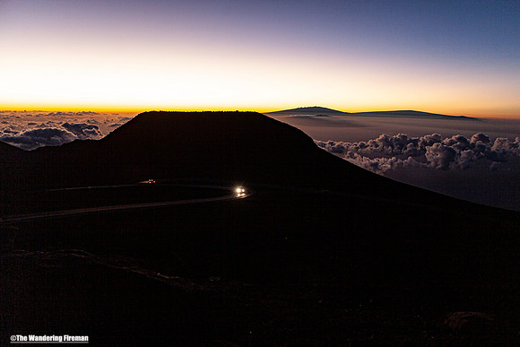 Two vehicles approach at sunrise on Haleakala Maui Hawaii