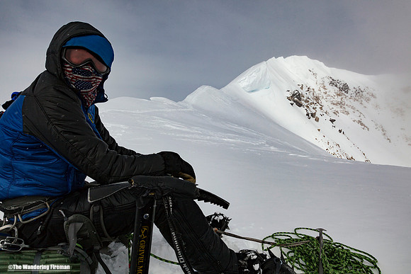 Sam Hennesey rests at the top of Pig Hill with summit ridge of Denali, Alaska, in view, as the highest mountain in North America