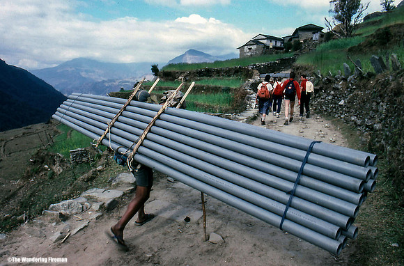 Porter carrying water pipes in Nepal