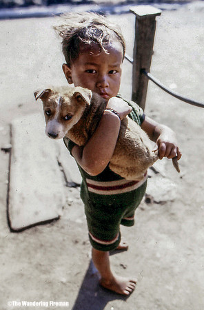 Young boy pulling a dogs tail in Nepal