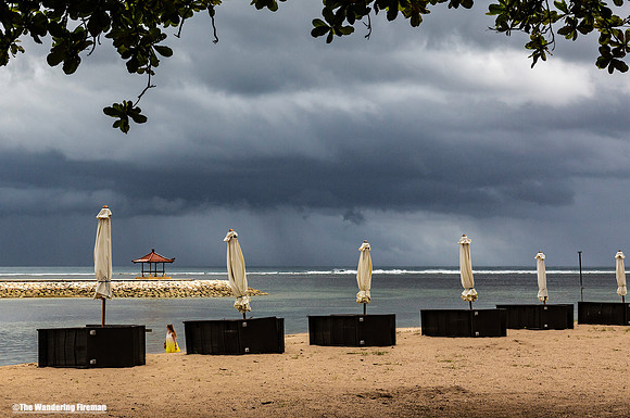 Woman in a yellow dress on a Bali Indonesia beach with a storm approaching