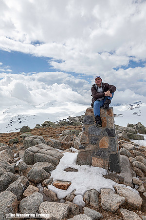Sitting atop the stone marker for the summit of Kosciuszko in Australia